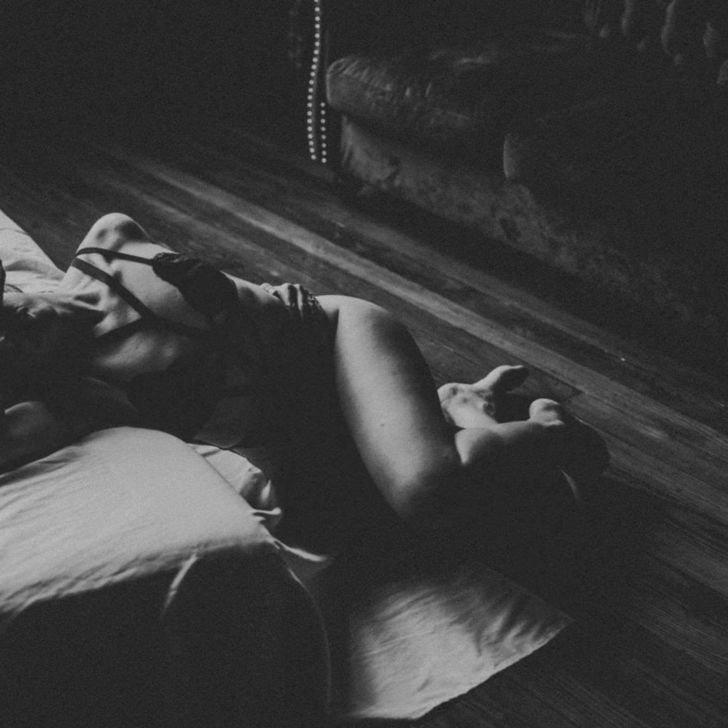 Sensual boudoir photo on hardwood floors at The Downtown Loft by Elevation Boudoir — client leaning into mattress, soft natural light, Tuscaloosa AL