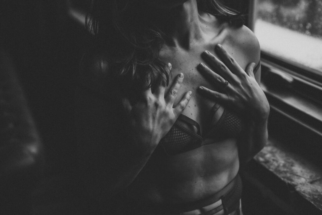 Black and white closeup at Elevation Boudoir in Tuscaloosa, Alabama — boudoir session detail with hands on collarbones in lace lingerie