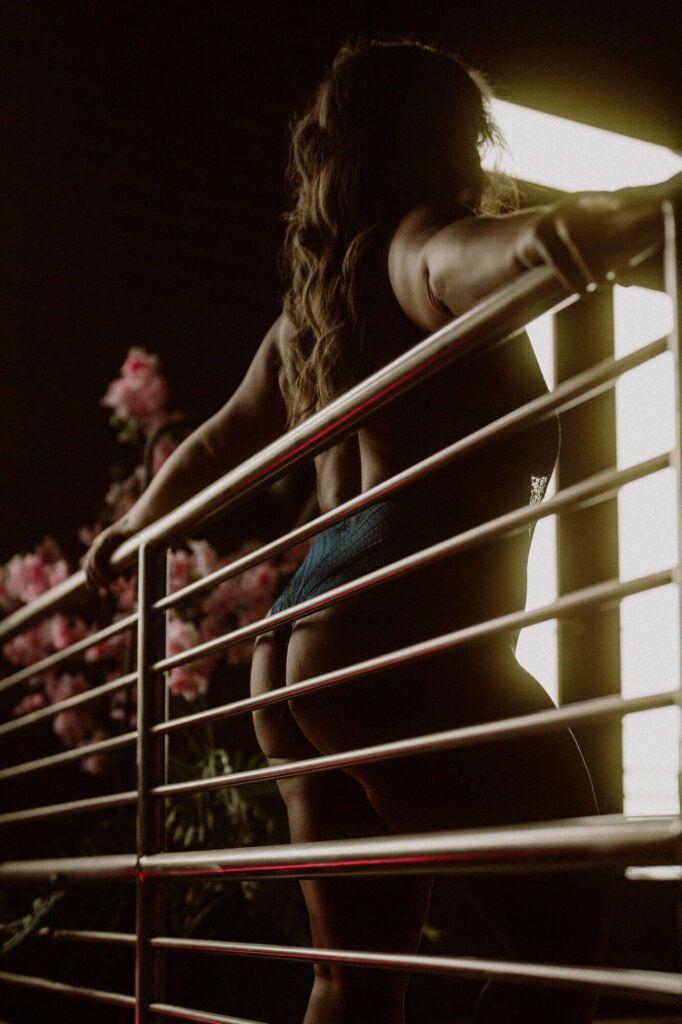 Backlit boudoir photo of a woman on a balcony wearing lace lingerie at Elevation Boudoir in Tuscaloosa, AL