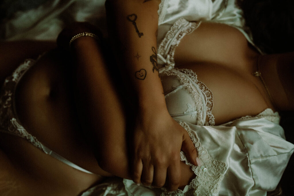 Closeup of bride’s hand gripping silk robe and lace lingerie during intimate bridal boudoir session at Elevation Boudoir
