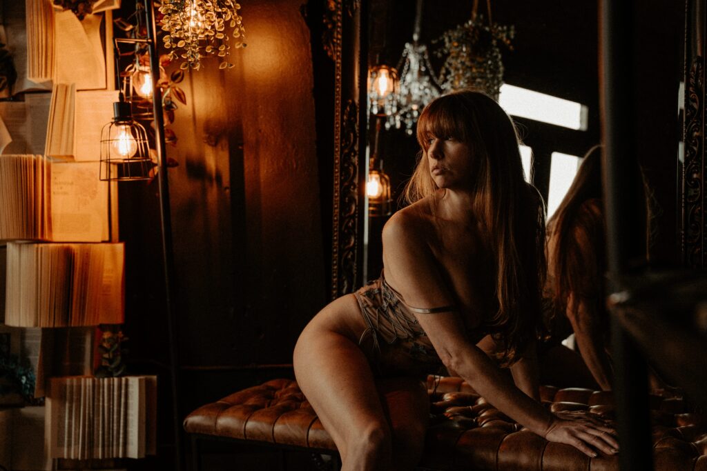 Luxury boudoir session featuring book wall backdrop and dramatic studio lighting in Tuscaloosa.