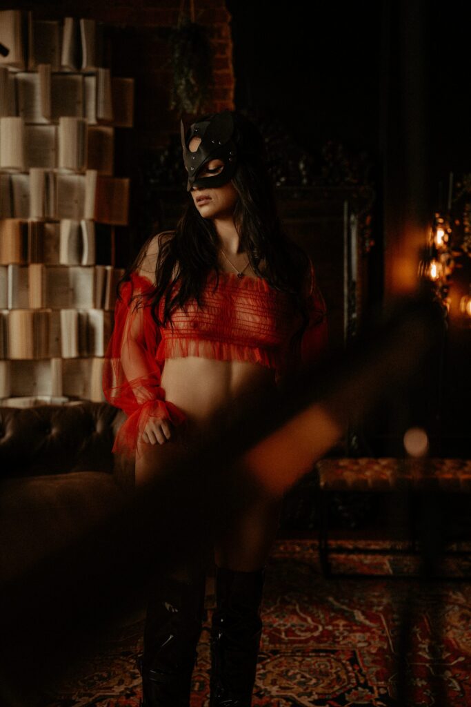 Moody book wall boudoir portrait with soft shadows and cinematic styling in Tuscaloosa Alabama.