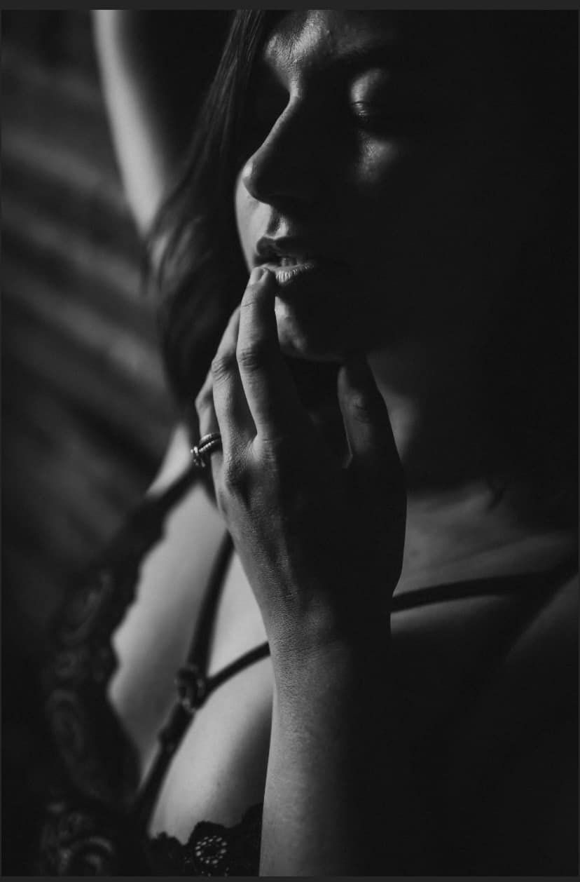 Black and white detail of a woman touching her lips for a boudoir session