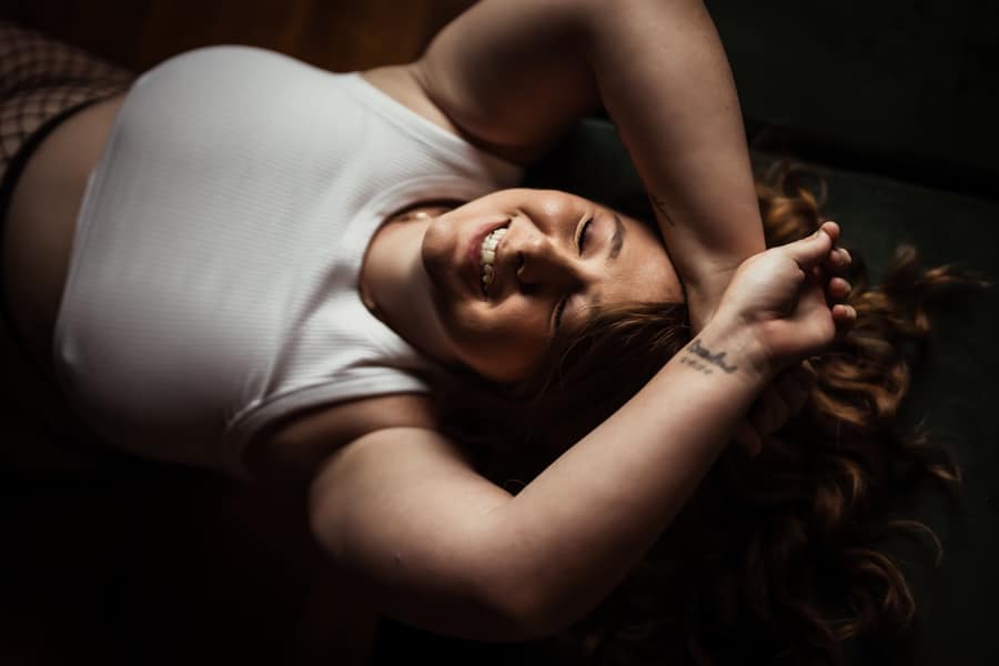 girl laughing while laying on her back posing for a boudoir photo